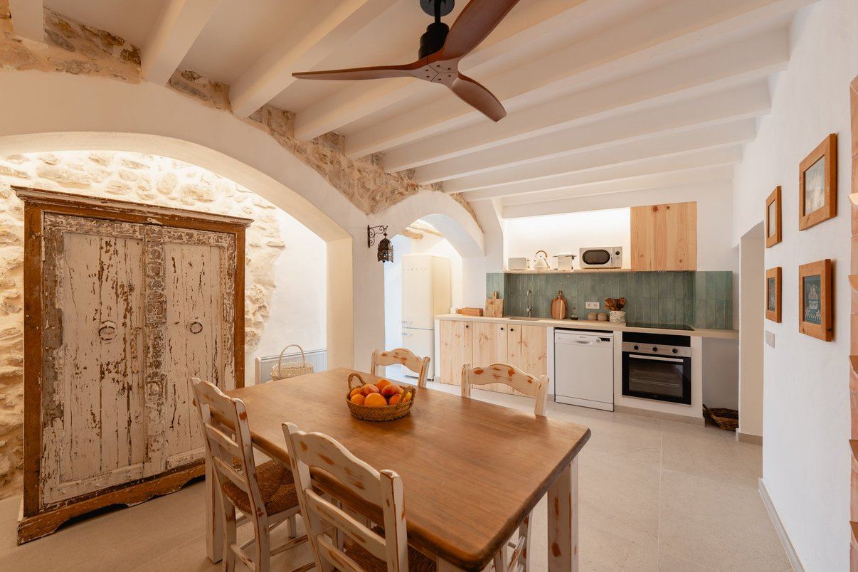 La cocina de madera clara, con la mesa del comedor y el botellero de barro.