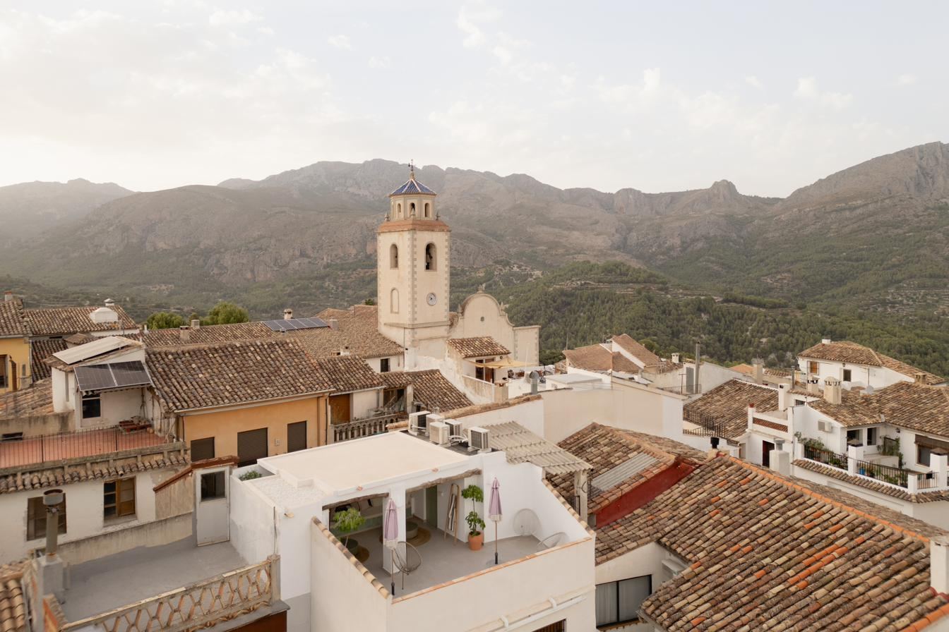 Benimantell desde el aire: tejados, el campanario y la sierra de Aitana detrás.