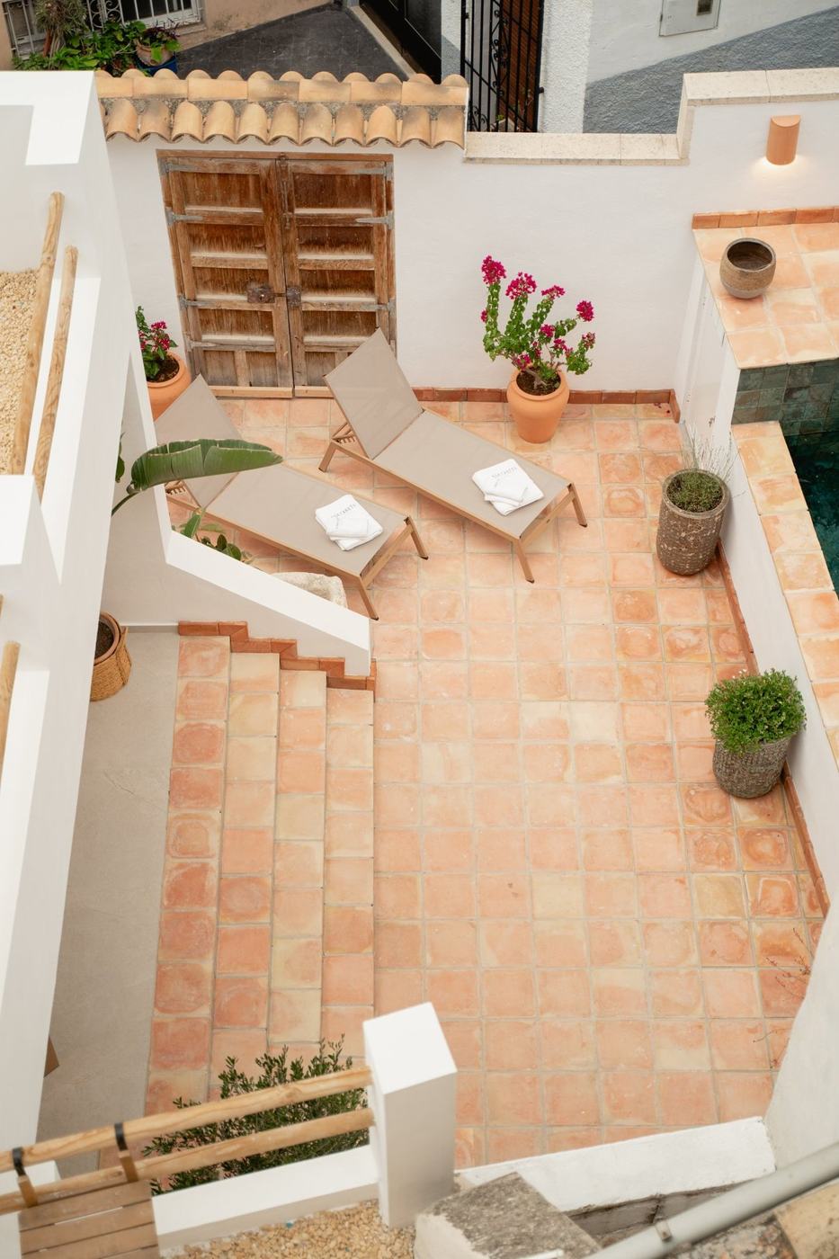 El patio desde arriba: tumbonas, suelo de barro cocido y buganvillas.