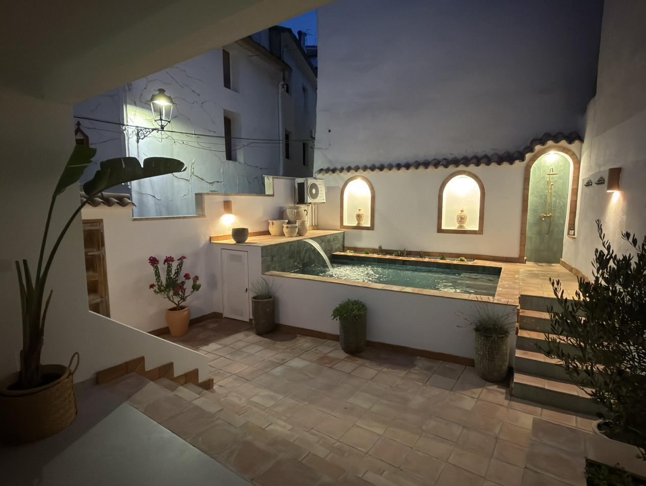 El patio al anochecer: la piscina iluminada y las hornacinas encendidas.