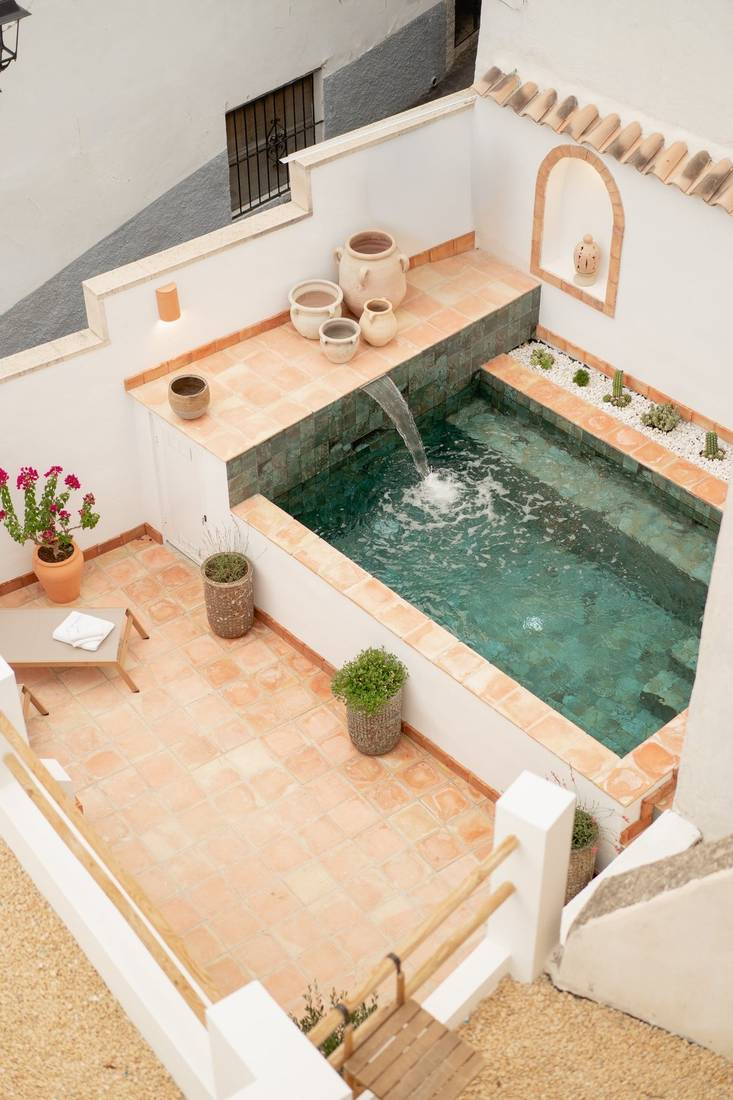 El patio desde arriba: la piscina con su caño, barro cocido y macetas.