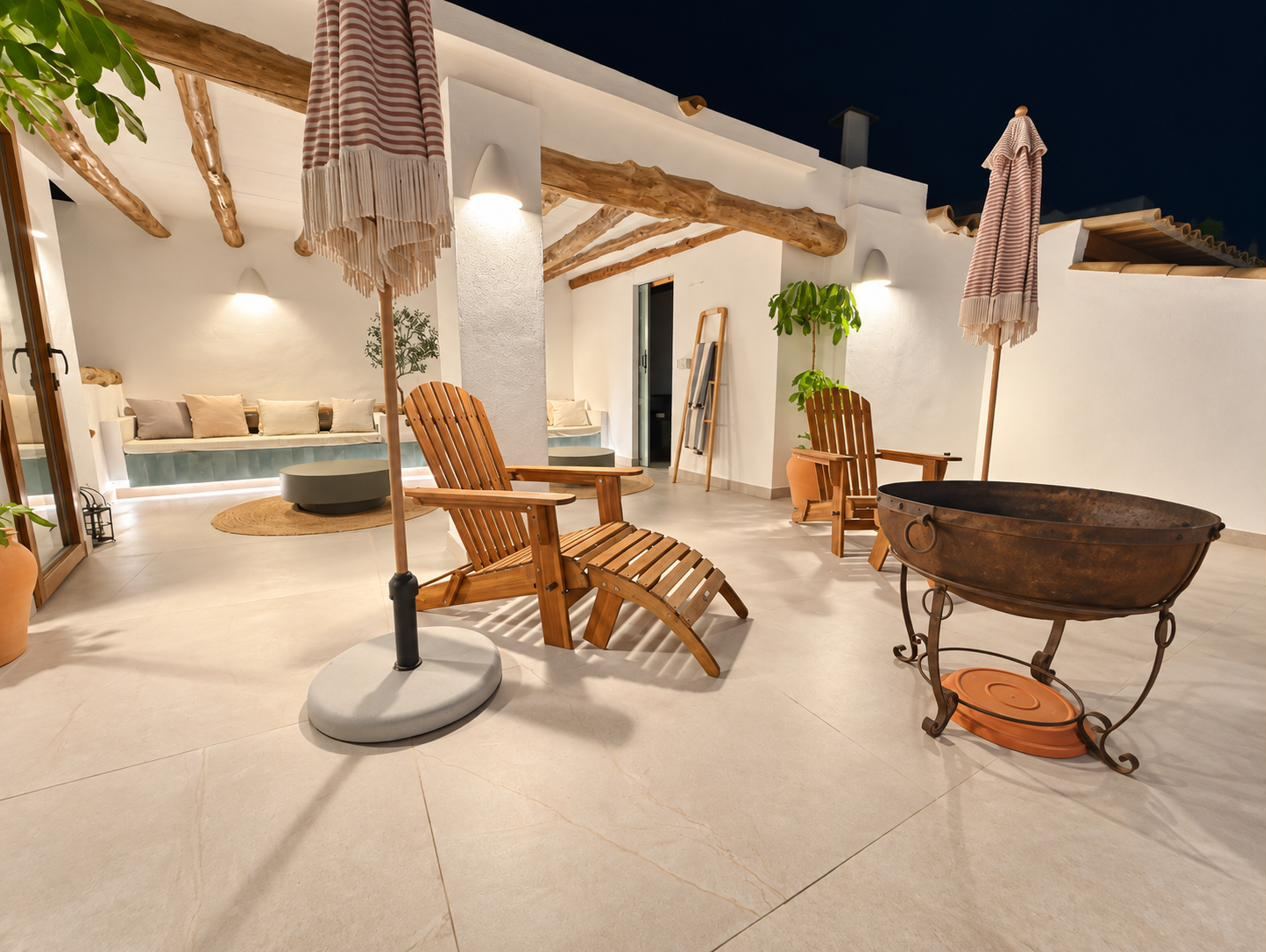 La azotea de noche: banco corrido bajo la pérgola, sillas de madera y el brasero.